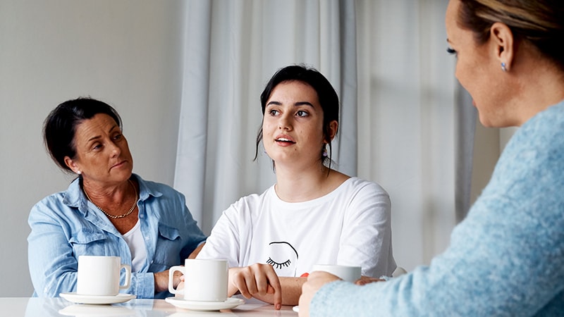 teen girl talking to mothers at kitchen table